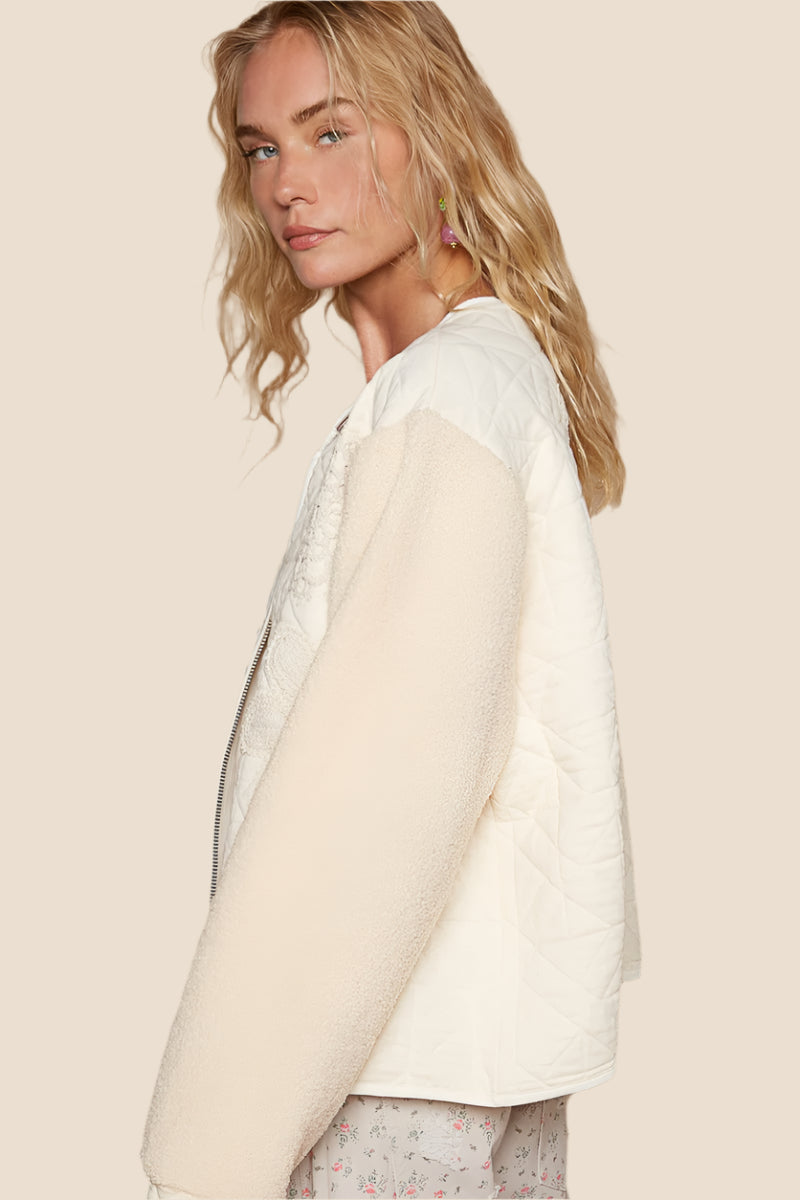 Imagine slipping into a quilted top with crochet appliques and furry sleeves – it’s like wrapping yourself in a cozy, stylish hug. The textured fabric feels warm and soft, perfect for those chill days when you just want to be comfortable but still look effortlessly chic. With the delicate crochet details, you can feel like a work of art, while the furry sleeves add that playful, free-spirited touch – it’s like you’re wearing a piece of whimsy.