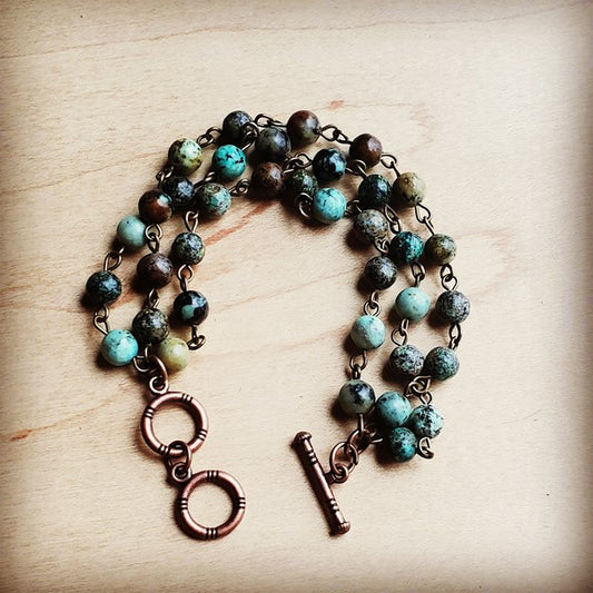  One of our FAV'S! The distinctive blue-green color with black or brown matrix inclusions, often featuring earthy greens and blues mixed with dark veins, makes a visually unique and highly valued African turquoise bracelet! Essentially this bracelet is variety of jasper with a mottled appearance. This triple strand bracelet is very intriguing with it's vibrant colors! 

THE INSIDE SCOOP:

Bracelet measures 7.5" in length end to end.
* Although your item will resemble the photo,  each piece 